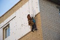 Rope access worker makes insulation with styrofoam