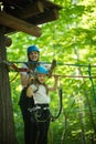 Rope adventure - a little girl and her mother standing on the stand attached to the tree near the rope bridge and Royalty Free Stock Photo