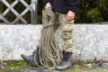 Rope on the background of an old tram stop with a man in his hands. camouflage pants, black army boots. Retro wooden construction