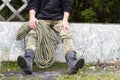 Rope on the background of an old tram stop with a man in his hands. camouflage pants, black army boots. Retro wooden construction