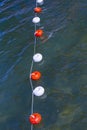 Rope with buoys above the surface of the blue water.  Bounding buoys at sea Royalty Free Stock Photo