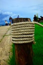 A rope coiled around wooden pole on Green grass background
