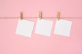 Rope with empty white paper frames with space for copy and clothespins on pink background Royalty Free Stock Photo