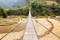 Rope hanging suspension bridge in Nepal with paddyfield and tourist Royalty Free Stock Photo