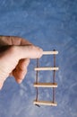 Rope ladder toy holding in adult hand on blue background. Climbing for success imaginations.