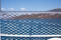 Rope net texture against blue sea background. A material net attached on safety pole that is a decoration on a yacht Royalty Free Stock Photo