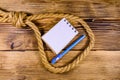 Rope with noose for the suicide, blank notepad and pen on wooden background