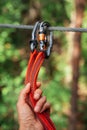 Rope park. The hand hooks the carabiners to the belay line. Close-up.