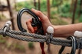 Rope park. The hand hooks the carabiners to the belay line. Close-up.