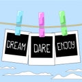 Rope with photo frames on cloudy sky background. Motivation words Dream, Dare, Enjoy on instant photos.