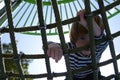 Rope slide for small children. A little boy climbs up the ropes. Child boy climbed on top of the rope web on playground.