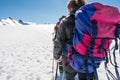 Rope team member point of view with mountaineers walking on snow and ice in sunny weather.