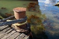 Rope is tied to an old rusty pillar of a dilapidated wooden jetty Royalty Free Stock Photo