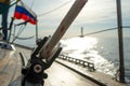 Rope with a winch on a wooden deck of a yacht on a blurred background of a boat on the horizon and the sea, on a summer Royalty Free Stock Photo