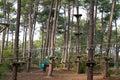 Ropes course in treetop adventure park passing hanging rope obstacle Royalty Free Stock Photo