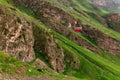 Ropeway in Caucasus Mountains. Red cable car moves down iron cable. Beautiful mountain landscape of Caucasus