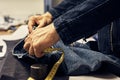 ropped image of tailor makes measurements of jeans with a meter at sewing workshop. Royalty Free Stock Photo