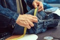 ropped image of tailor makes measurements of jeans with a meter at sewing workshop. Royalty Free Stock Photo