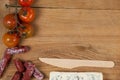 Roquefort cheese, wooden knife, cherry tomatoes and meat on chopping board Royalty Free Stock Photo