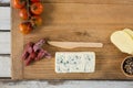 Roquefort cheese, wooden knife, cherry tomatoes and meat on chopping board Royalty Free Stock Photo