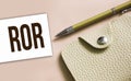ROR abbreviation written on a business card, pen and beige leather wallet. Financial business concept