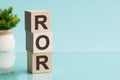 ROR - Rate Of Return. Wooden blocks with the word ROR, blue background