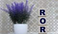 ROR word on cubes on a gray background and lavender bush