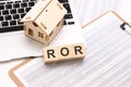 ROR - word on wooden cubes on a white background with a table, laptop keyboard and a small wooden house