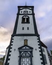 Roros Church towers into the heavens, its classic clock face and ornate entrance a focal point against the twilight sky in this Royalty Free Stock Photo