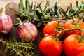 Rosa Bianca eggplants with tomatoes on branch over a wooden board with green olives on branch with leaves and rosemary twig. Royalty Free Stock Photo