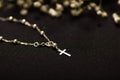 Rosary beads with blurred white small flowers, black background Royalty Free Stock Photo