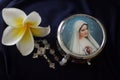 Rosary beads with Jesus Christ holy cross crucifix and portrait of Mother Virgin Marry on rosary box cover with a flower. Royalty Free Stock Photo