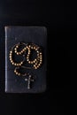 Rosary beads and prayer book on dark background