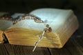Rosary and bible on vintage wooden table by night