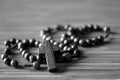 The Rosary. Close up of wooden rosary beads with Jesus Christ holy cross Crucifix on the table in black and white background.