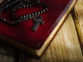 A rosary with a cross lies on a red book - the Holy Bible on a wooden table. Close-up. Religion, Christianity, Catholicism, faith Royalty Free Stock Photo