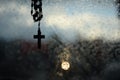 Rosary and cross, wet window and lights of an motorbike