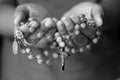 Rosary in hand in black and white. Young junior lady holding rosary with open hand with Jesus Christ Cross Crucifix. Month of