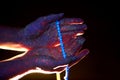 Rosary in hand, prayer. Light through the palms of your hands in ultraviolet, God and religion, beads. Divine light through your Royalty Free Stock Photo