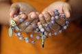 Rosary in hand. Young junior lady holding rosary with open hand. Female hands holding a rosary with Jesus Christ Cross or Crucifix