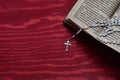 Rosary with old ancient book on red wood Royalty Free Stock Photo