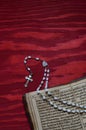 Rosary with old ancient book on red wood Royalty Free Stock Photo