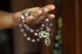 Rosary in one hand. Young junior lady holding rosary with open hand. Female hands holding a rosary with Jesus Christ Cross or