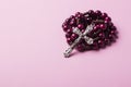 Rosary on a pink background. Cross.