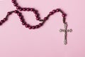 Rosary on a pink background. Cross.