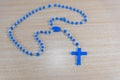 Rosary and blue Catholic crucifix on wooden background