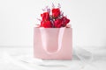 Rose bouquet with pink gift paper bag on white table Royalty Free Stock Photo