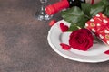 Rose and a box in gift paper on a white plate, a bottle of red wine and glasses, concept for Valentines Day Royalty Free Stock Photo