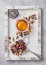 Rose buds mix tea on cup shape ceramic plate in wooden box with tea ball strainer infuser and glass cup on white background