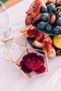 Rose in a case, a box for rings, on a table with a whatnot with grapes and pomegranates at a wedding.